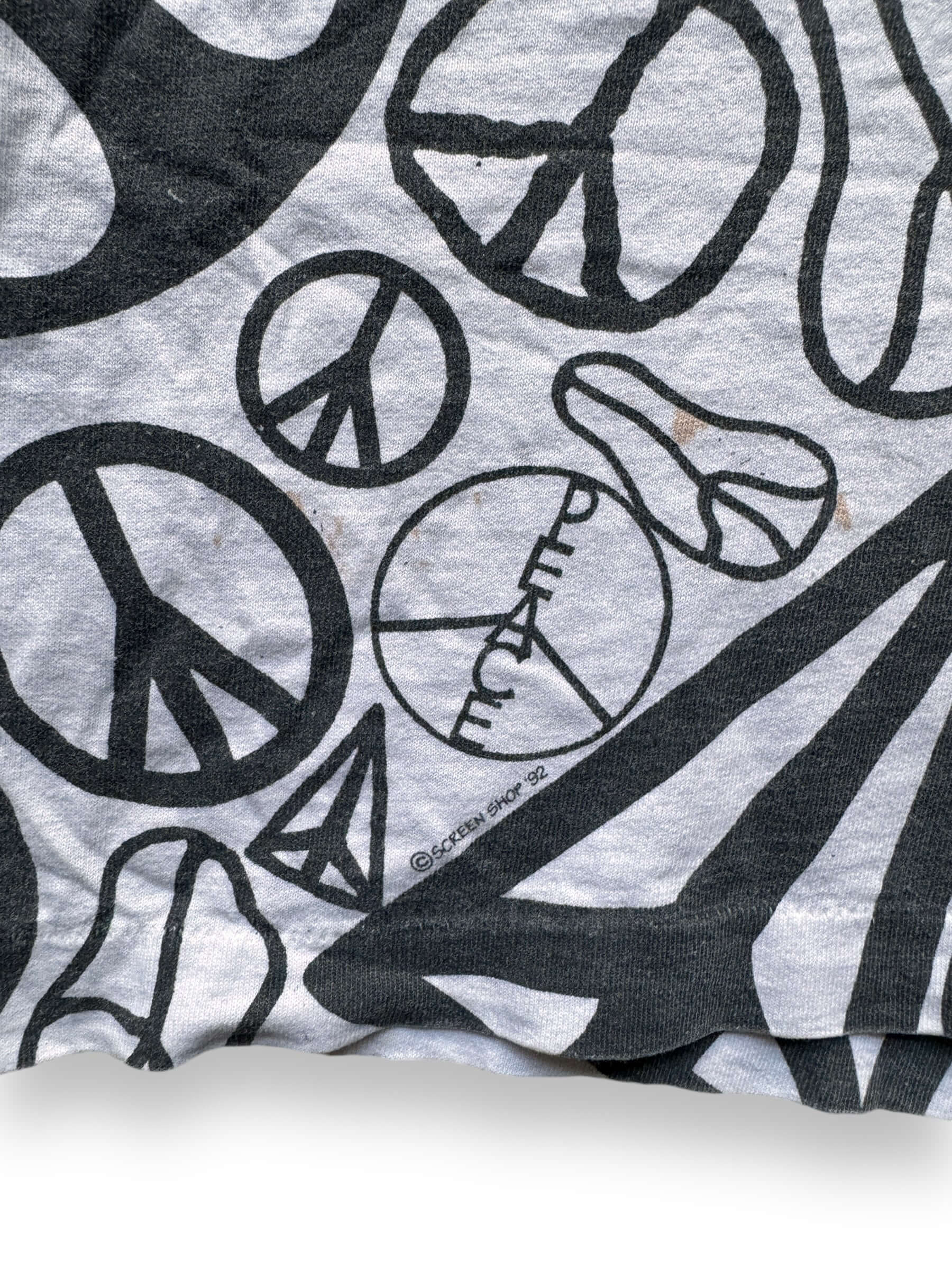 Screen Shop 1992 and small stain on front of Vintage Single Stitch Peace Sign AOP Tee SZ XL