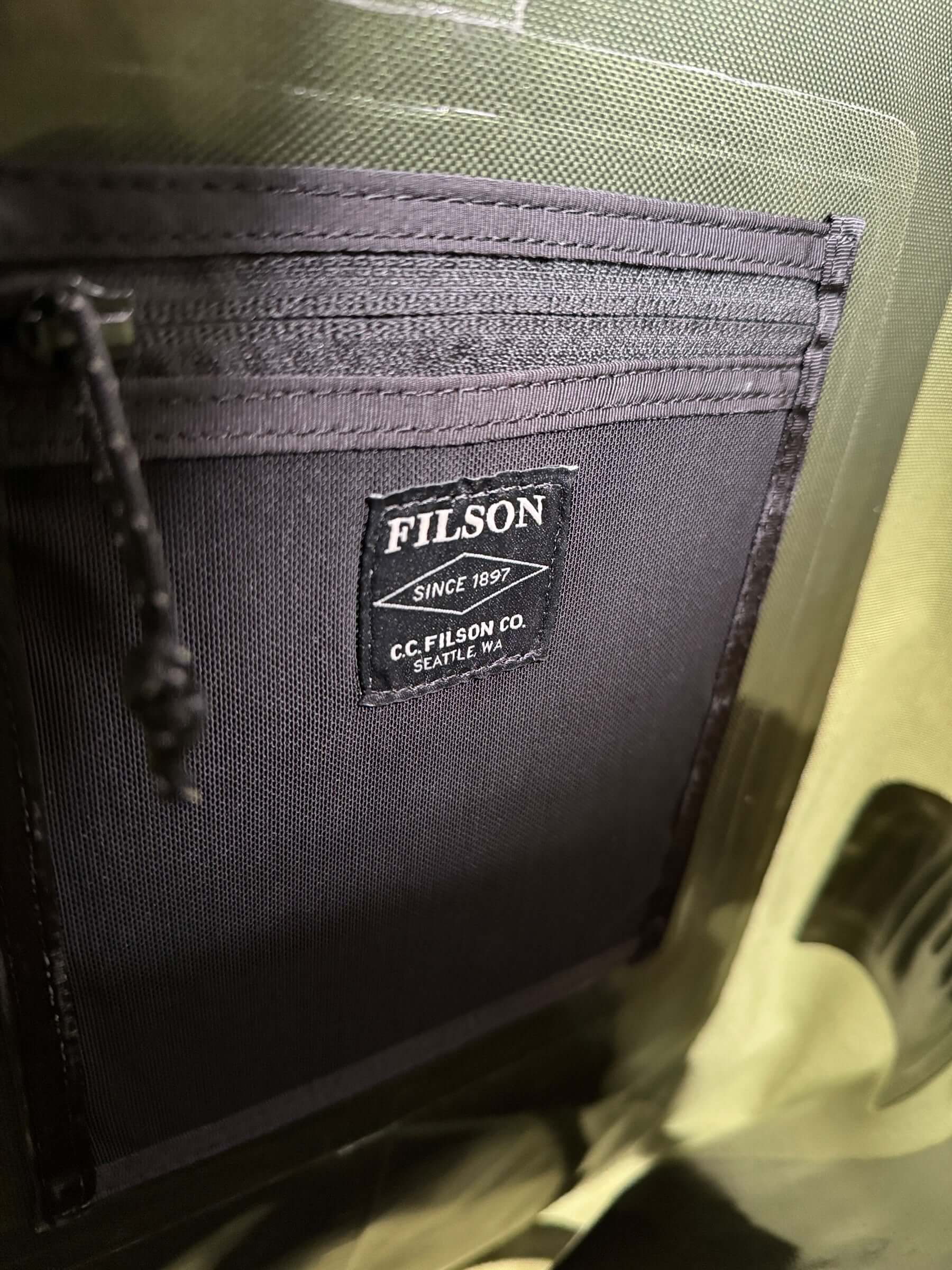 Inner pockets and brand tag on Filson NWT Green Dry Backpack